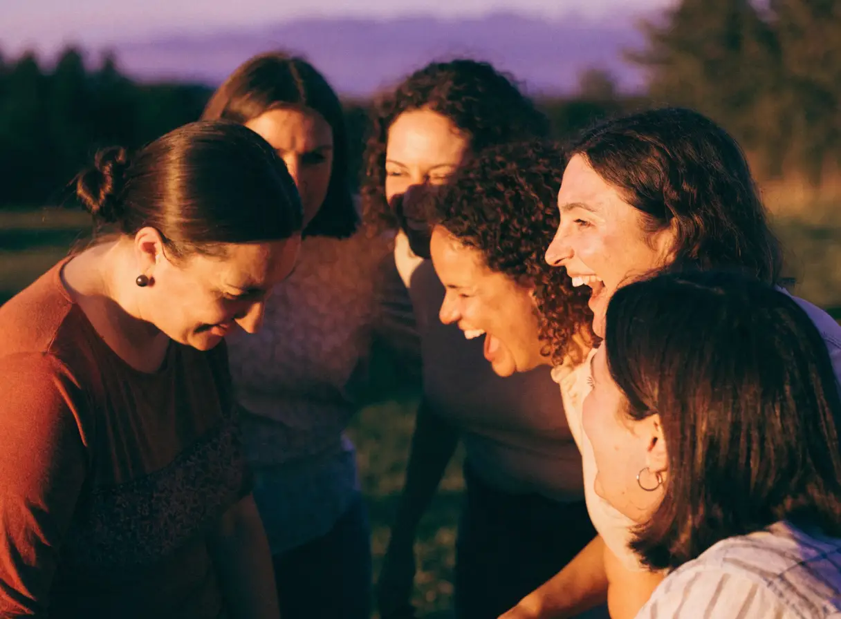 Women laughing together outdoors at dusk